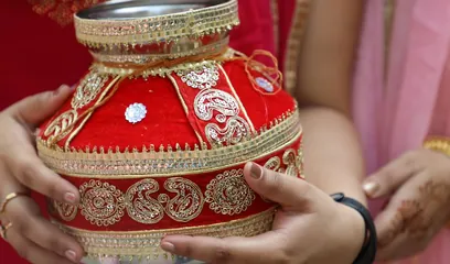 Karva Chauth: hands holding a decorated red karva pot