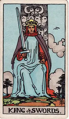 King of Swords. A crowned king sits square on his throne holding an upright sword slightly tilted, two butterflies carved behind him.