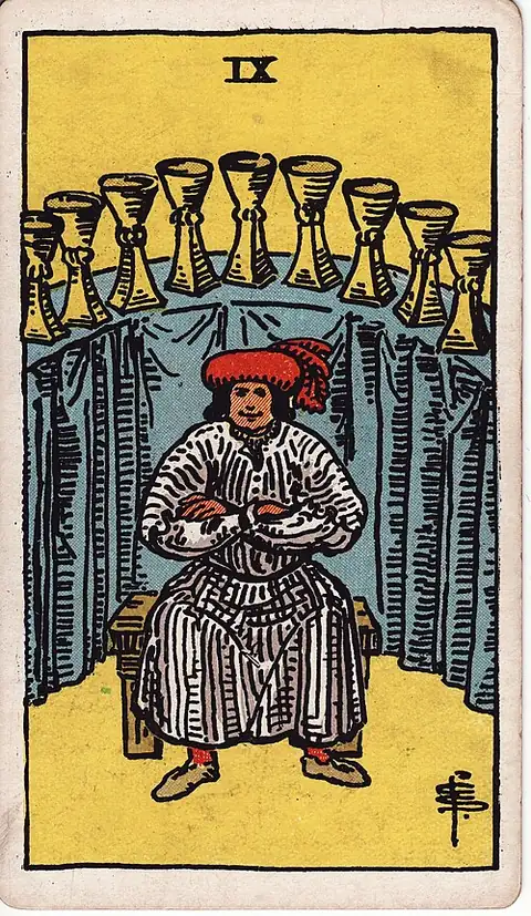 Nine of Cups. A well-fed man sits arms folded on a bench with nine cups arched on a covered table behind him.