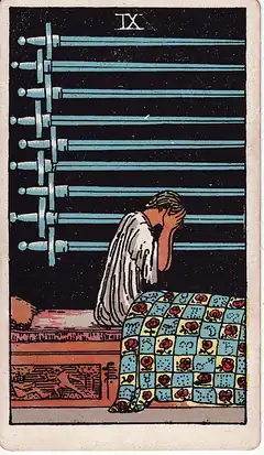 Nine of Swords. A figure sits up in bed with the face in both hands, nine swords hanging on the wall behind in the dark.