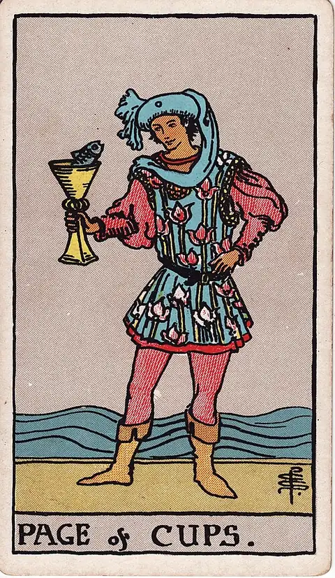 Page of Cups. A young figure in a flowered tunic holds up a cup with a fish looking out of it, the sea behind.