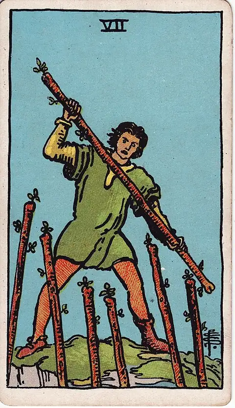 Seven of Wands reversed. A man on high ground defends himself with a staff against six more thrust up at him from below.