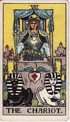 The Chariot. An armoured figure rides a canopied chariot drawn by one black sphinx and one white, holding no reins, with a walled city behind.