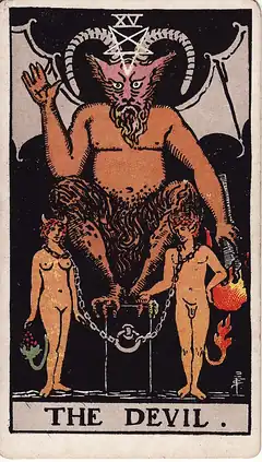 The Devil. A horned figure squats on a block above a naked man and woman loosely chained to it by the neck, both grown small horns and tails.