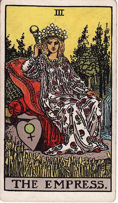 The Empress reversed. A crowned woman reclines on cushions in a field of ripe wheat, a shield with the sign of Venus beside her and a wood and waterfall behind.
