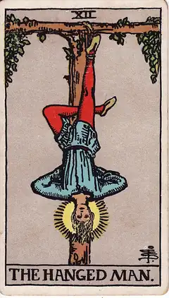 The Hanged Man. A man hangs upside down by one ankle from a living T-shaped tree, the free leg crossed behind, his face calm and haloed.