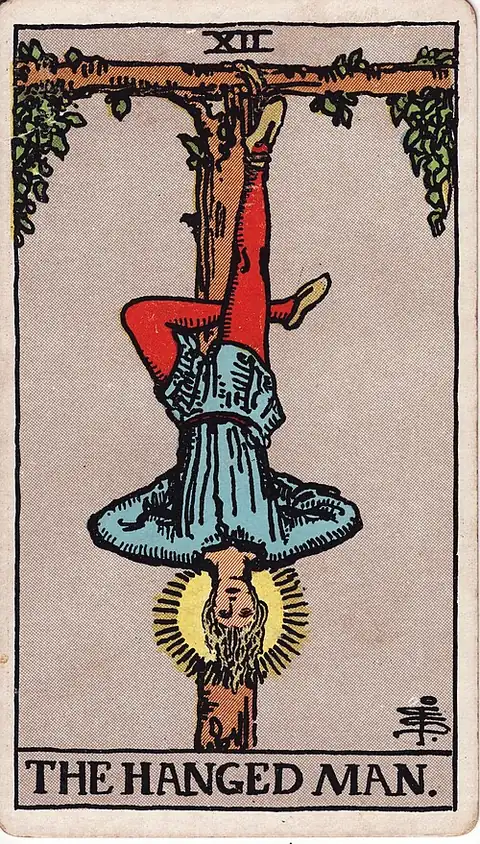 The Hanged Man. A man hangs upside down by one ankle from a living T-shaped tree, the free leg crossed behind, his face calm and haloed.