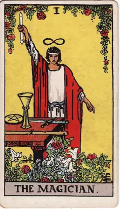 The Magician. A figure stands at a table of cup, coin, sword and wand, one arm raised to the sky and the other pointing to the ground, with a lemniscate above the head and roses and lilies below.
