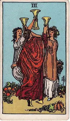 Three of Cups. Three women raise their cups together in a circle among vines and fruit.